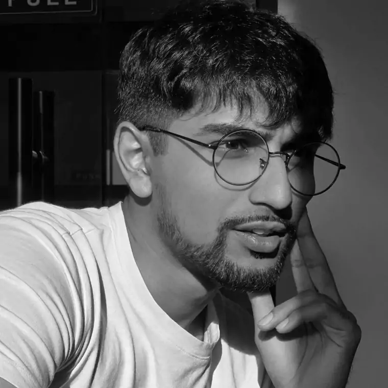 Portrait of Afsah in round glasses, a hand at the chin.